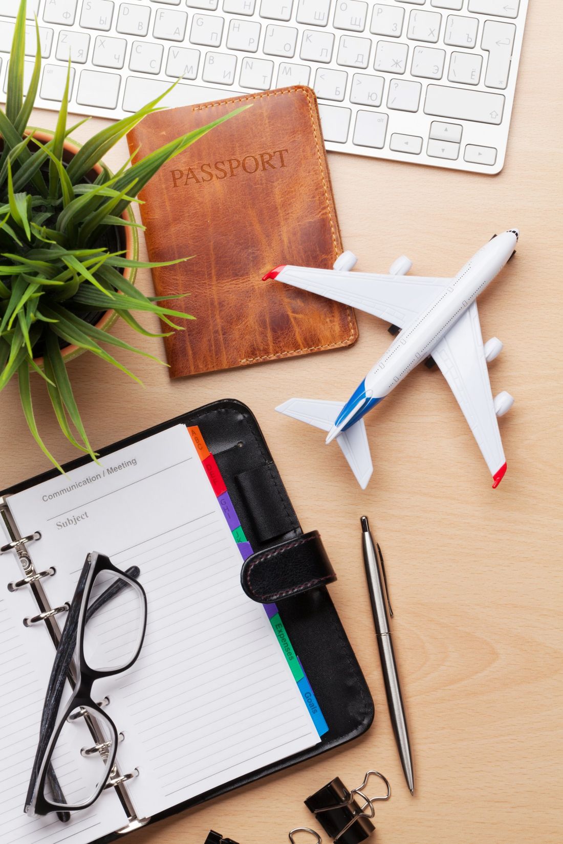 Mesa de planejamento de viagem com passaporte, avião em miniatura e agenda
